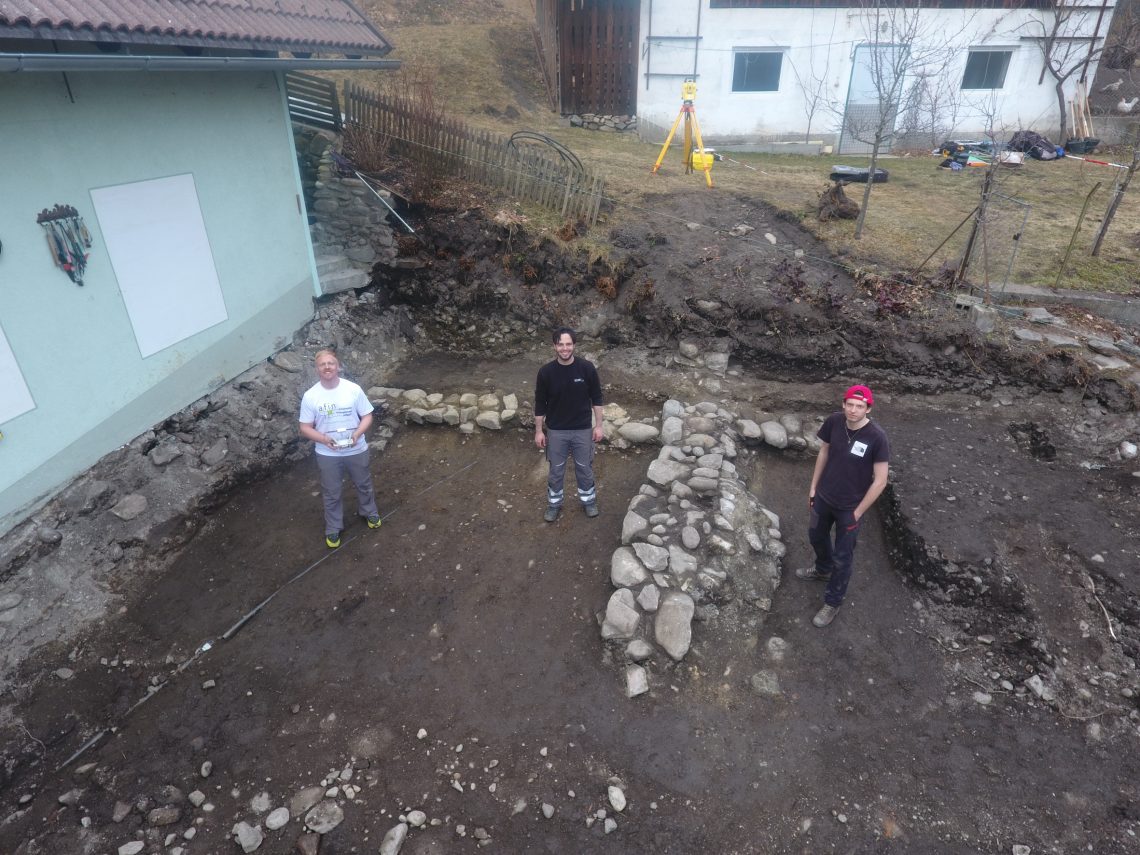 Grabungsteam (v. l. Stefan Pircher, Daniel Simunovic und Niklas Angermann) mit den Fundamenten des spätantiken Hauses in der Flur Klammer im Hintergrund (Foto: Stefan Pircher).